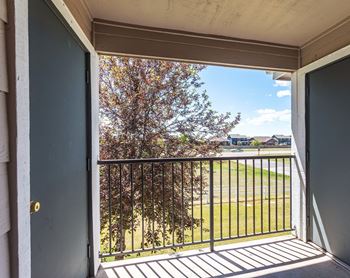 a balcony with a view of a grassy area and a tree